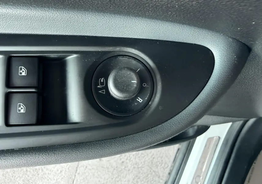 Gros plan sur les commandes de réglage des rétroviseurs et des vitres côté conducteur de l'Opel Mokka X blanc.