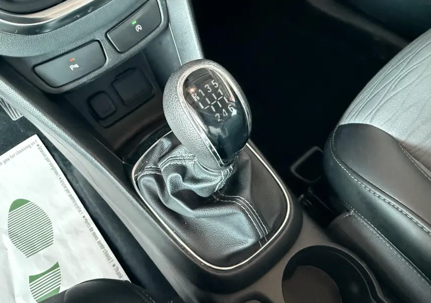 Gros plan sur le levier de vitesse manuel noir et gris à six rapports de l’Opel Mokka X 2016, intérieur tissu cuir gris-noir.