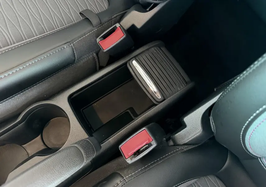 Vue rapprochée de la console centrale noire avec accoudoir coulissant et ceintures de sécurité rouges dans l’Opel Mokka X.