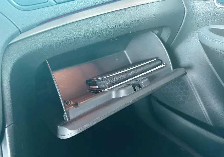 Gros plan sur la boîte à gants ouverte côté passager de l’Opel Mokka X 2016 avec un carnet noir à l’intérieur.