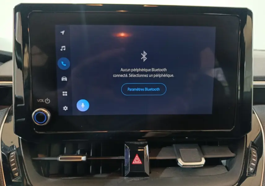 Écran tactile central allumé avec menu Bluetooth sur le tableau de bord de la Toyota Corolla hybride blanche.