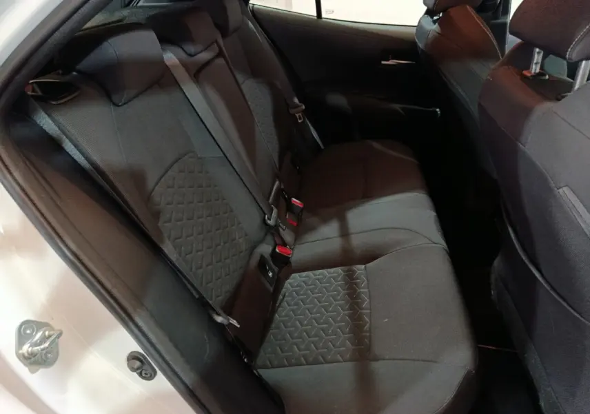 Vue intérieure côté gauche des sièges arrière noirs d'une Toyota Corolla Hybride 2022 blanche, porte ouverte.