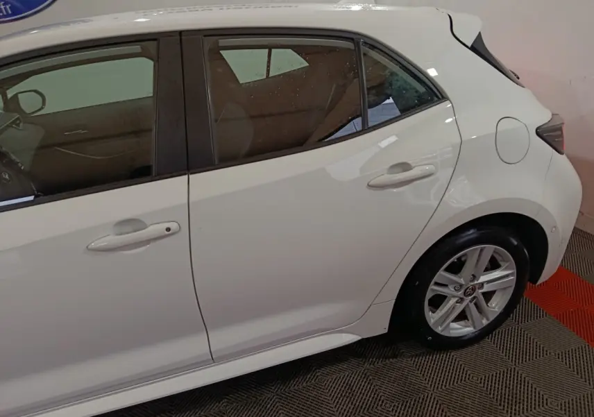 Profil droit de la Toyota Corolla hybride blanche 2022, mettant en valeur les portes arrière et la roue arrière.