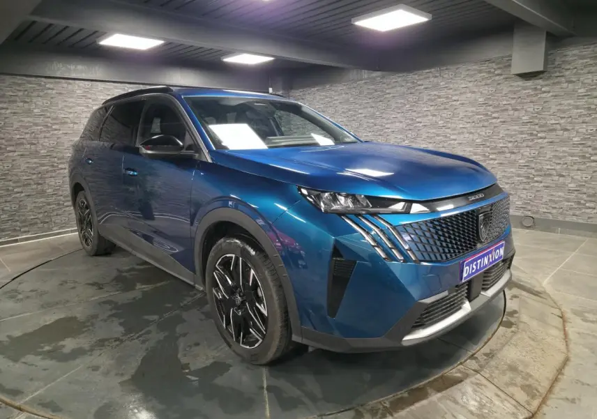 Peugeot 5008 bleu métallisé vue 3/4 avant droit en intérieur avec jantes alliage noires et calandre noire.