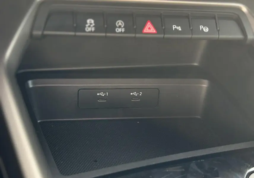 Gros plan sur la console centrale noire de l'Audi A3 Sportback 2023 avec ports USB-C et boutons de contrôle au-dessus.