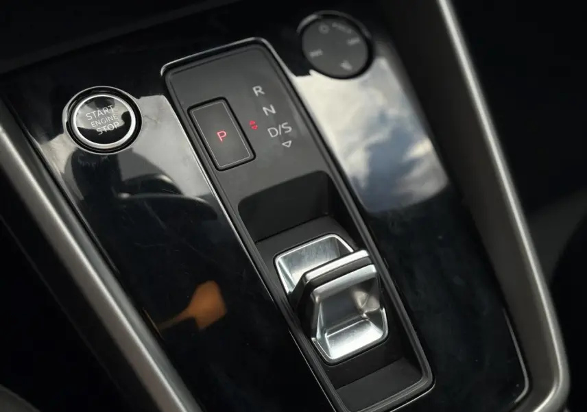 Gros plan sur la console centrale noire brillante de l'Audi A3 Sportback 30 TFSI 2023 avec levier de boîte auto et bouton start/stop.