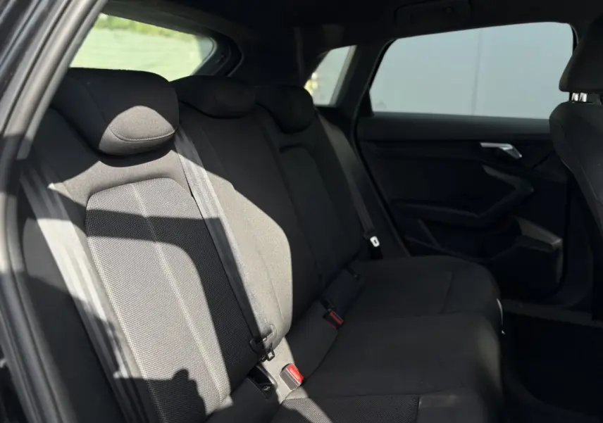 Vue intérieure arrière de l'Audi A3 Sportback 2023 en Noir Mythe, montrant les sièges arrière en tissu sombre.