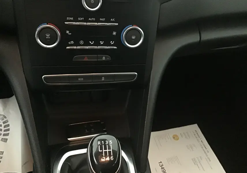 Console centrale de Renault Megane IV Berline blanche 2019, vue sur levier de vitesse manuel et commandes climatisation.
