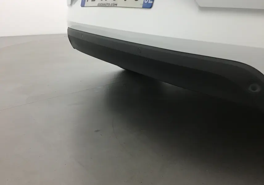 Vue rapprochée du pare-chocs arrière blanc de la Renault Mégane IV Berline avec plaque d'immatriculation française visible.