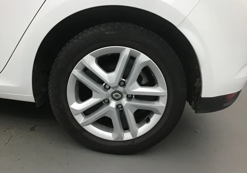 Gros plan sur la roue arrière droite blanche d'une Renault Mégane IV Berline 2019 avec jante alliage siglée Renault.