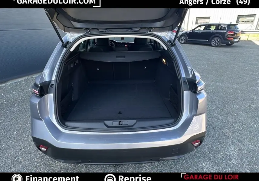 Coffre ouvert vu de l’arrière d’une Peugeot 308 gris clair, montrant un espace de chargement spacieux et propre.