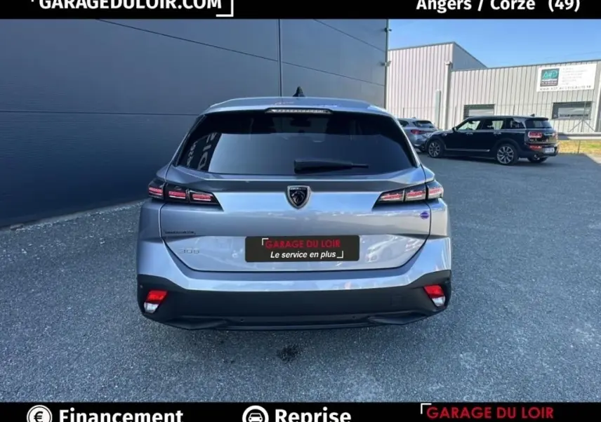 Vue arrière d'une Peugeot 308 gris clair 2023 avec feux LED et lunette arrière teintée sur parking extérieur.