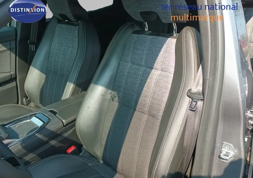 Vue intérieure côté conducteur du Renault Austral 2025, sièges en cuir noir et tissu gris, avec console centrale visible.