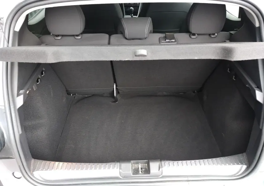 Coffre ouvert vu de l'arrière d'une Dacia Sandero gris 2024, montrant l'espace de chargement et la banquette arrière.