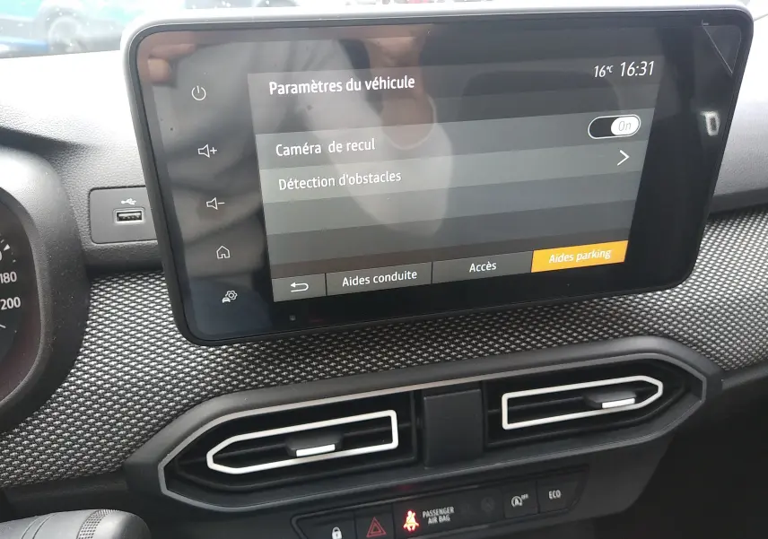 Écran tactile central du tableau de bord de la Dacia Sandero 2024 affichant les paramètres d’aides au stationnement.