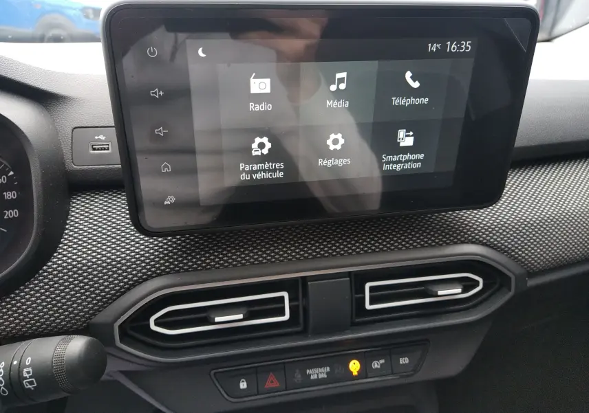 Écran tactile central du tableau de bord de la Dacia Sandero gris, affichant les options multimédia et réglages.