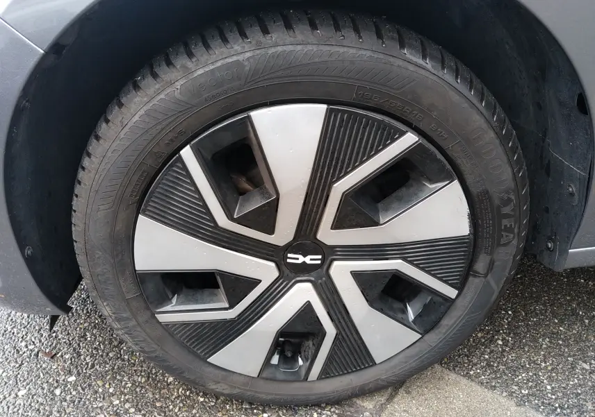 Gros plan sur la roue avant gauche d'une Dacia Sandero gris 2024, mettant en valeur la jante au design moderne bicolore.