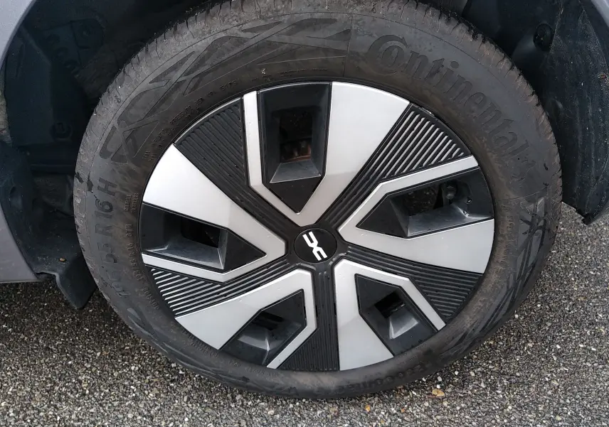 Gros plan sur la roue avant gauche de la Dacia Sandero gris 2024, mettant en valeur la jante au design géométrique noir et argent.