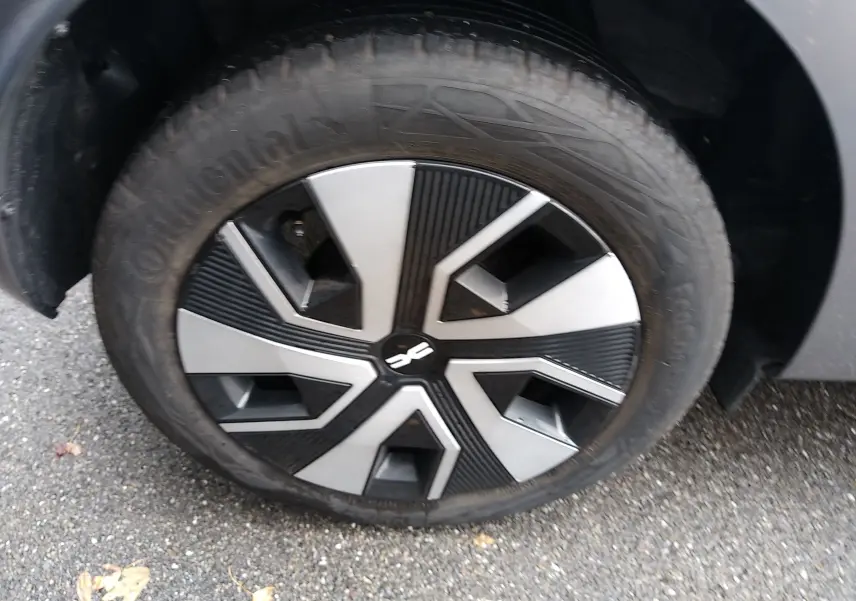 Gros plan sur la roue avant droite d'une Dacia Sandero gris 2024 avec jante au design noir et argenté.