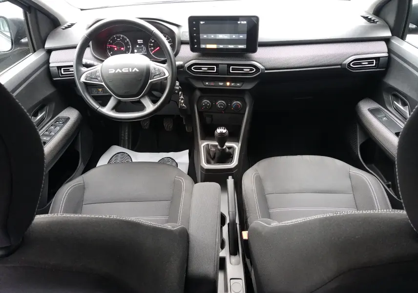 Vue intérieure avant de la Dacia Sandero 2024 gris, avec tableau de bord moderne, écran tactile et boîte manuelle.