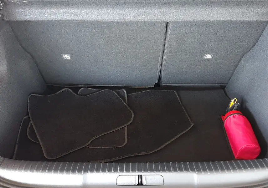 Coffre ouvert d'une DS3 Crossback gris platinium, montrant tapis noirs et trousse de secours rouge.