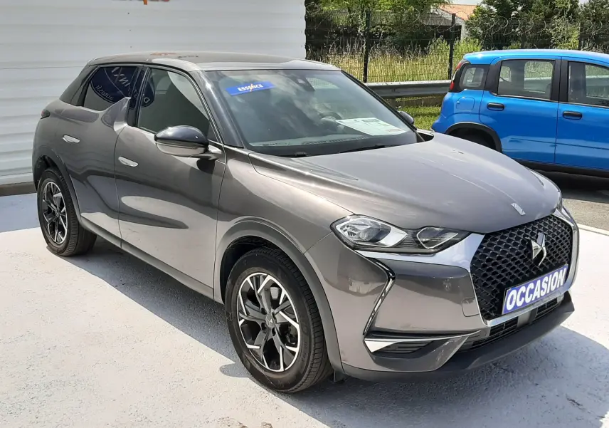 DS3 Crossback gris platinium métal en 3/4 avant droit, avec calandre distinctive et jantes bi-ton élégantes.