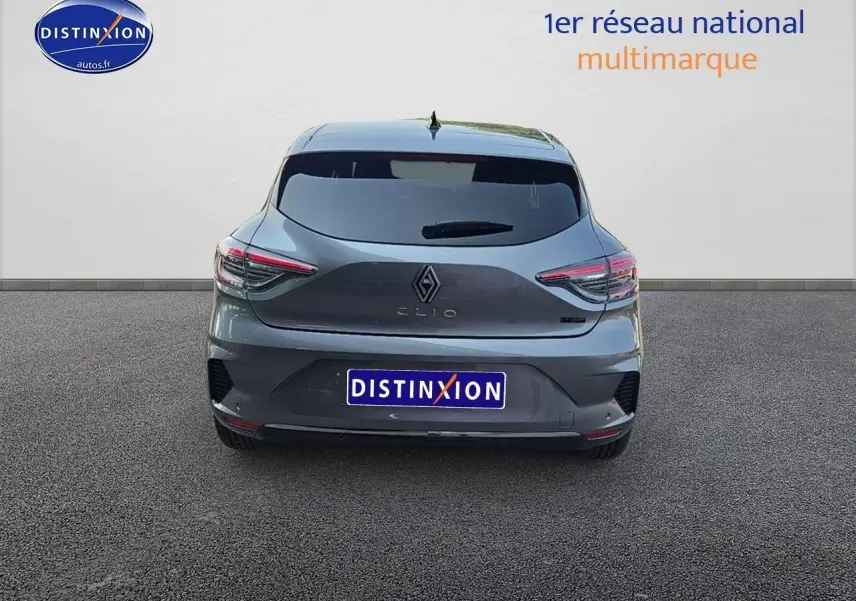 Vue arrière d'une Renault Clio V gris schiste avec feux LED et becquet arrière, stationnée sur sol gris.