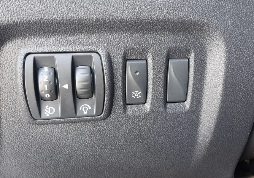 Gros plan sur les commandes de réglage des phares et du système start-stop du Renault Captur 2018, intérieur noir.