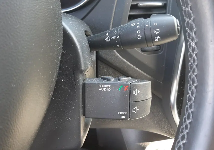 Gros plan sur la commande audio au volant et le commodo d'essuie-glace du Renault Captur gris cassiope 2018, intérieur noir.