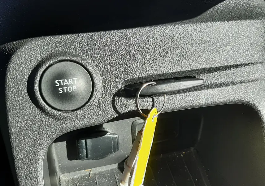 Gros plan sur le bouton Start/Stop et la clé insérée dans la poignée de la console intérieure noire du Renault Captur gris cassiope.