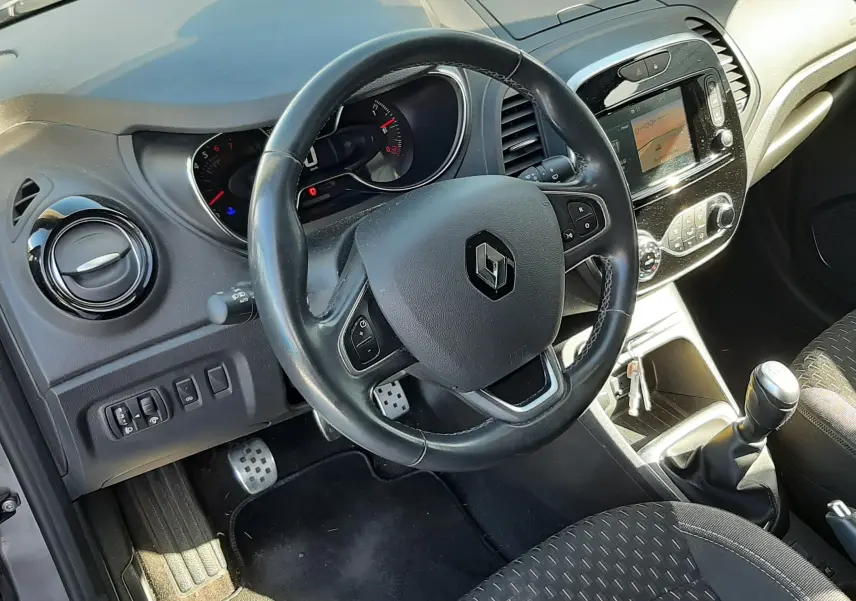 Vue intérieure côté conducteur du Renault Captur 2018, tableau de bord noir avec volant multifonction et levier de vitesse manuel.