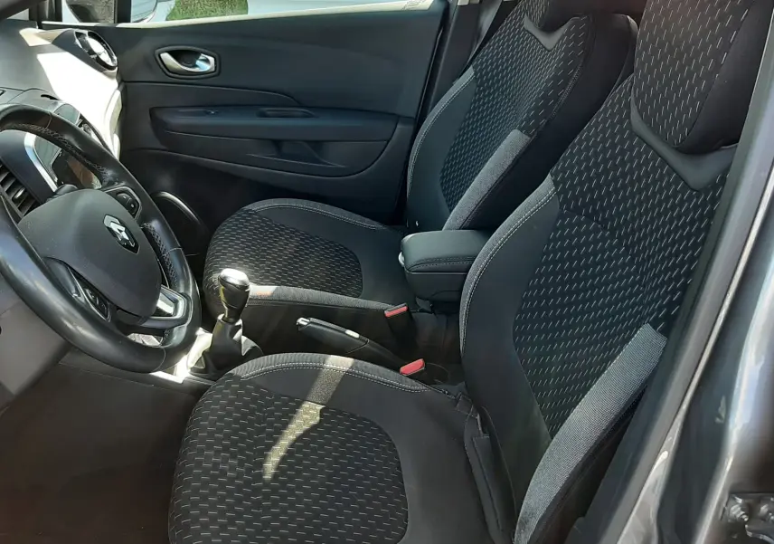 Vue intérieure côté conducteur du Renault Captur 2018, sièges noirs à motifs et volant avec logo Renault visible.