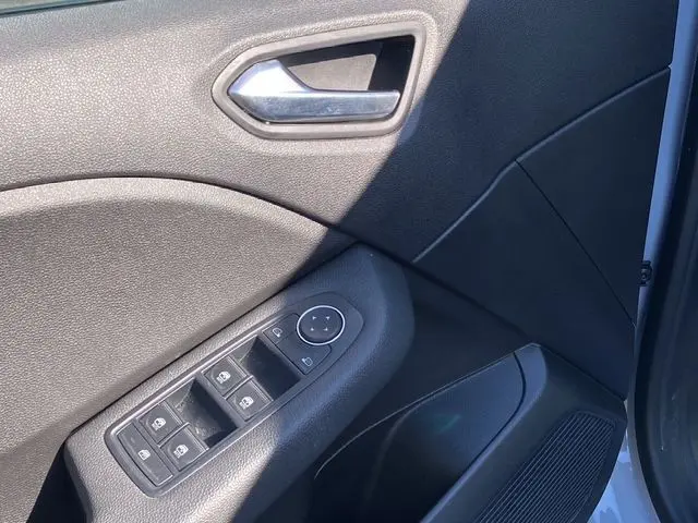 Détail de la porte avant gauche gris rafale de la Renault Clio V avec commandes électriques des vitres et poignée argentée.