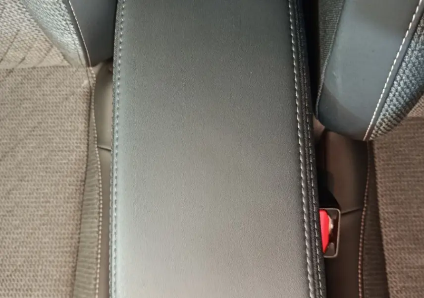 Accoudoir central avant en cuir noir entre les sièges tissu gris foncé de la Peugeot 208 2025.