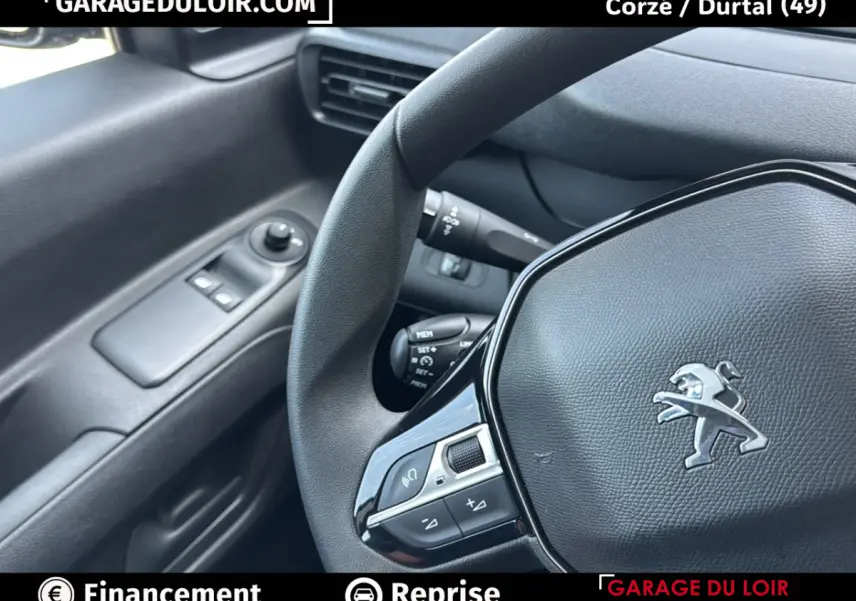 Vue rapprochée de l’intérieur du Peugeot Rifter 2024, volant cuir avec logo lion et commandes intégrées côté gauche.