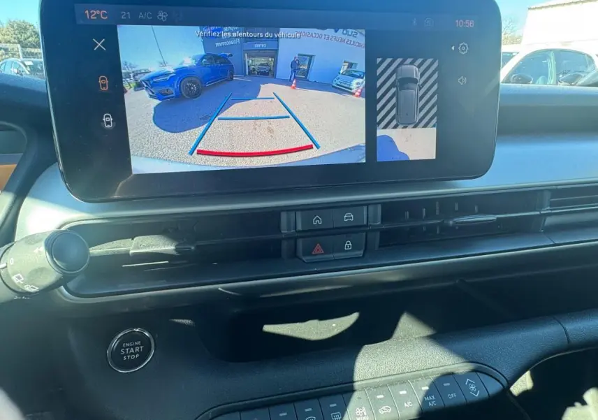 Vue intérieure du tableau de bord du Jeep Avenger gris 2025, écran tactile affichant la caméra de recul et commandes climatisation.