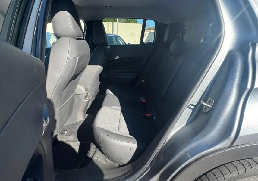 Vue intérieure arrière côté gauche du Jeep Avenger gris 2025, montrant les sièges arrière et la portière ouverte.