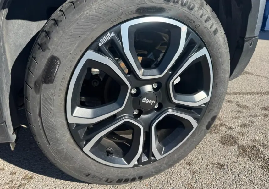Gros plan sur la roue avant droite du Jeep Avenger gris, mettant en valeur le pneu Goodyear et l'aile du véhicule.