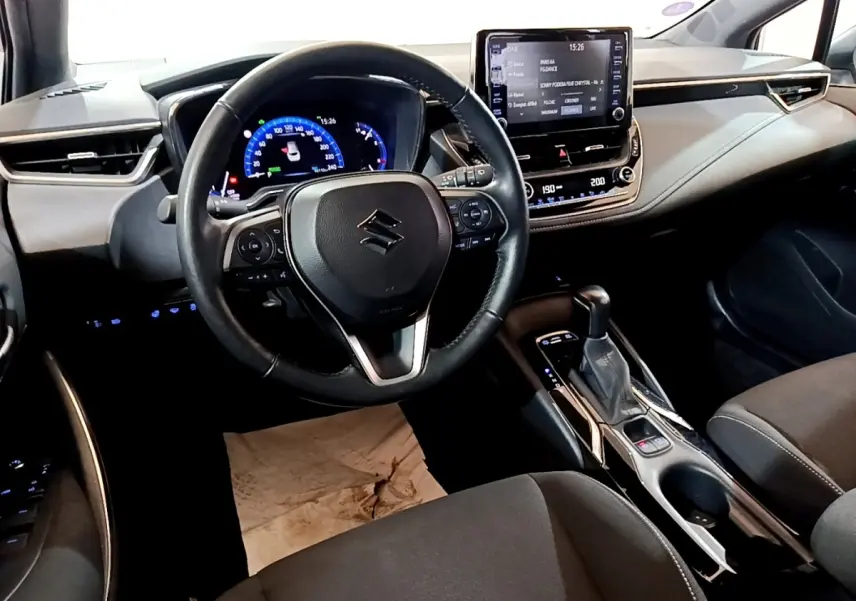 Vue intérieure du poste de conduite de la Suzuki Swace 1.8 Hybrid Privilege avec volant cuir multifonctions et écran tactile central.