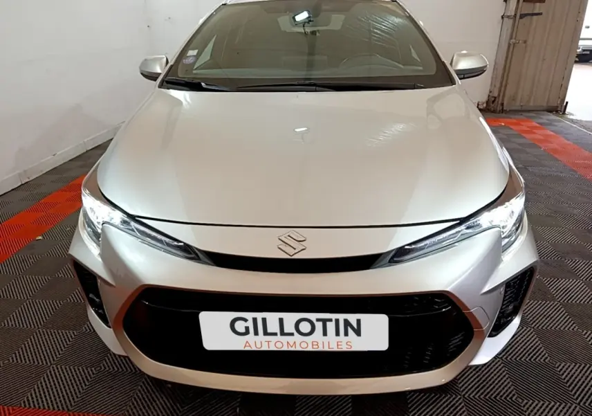 Vue avant rapprochée d'une Suzuki Swace 1.8 Hybrid Privilege gris clair avec calandre noire et phares LED allumés.