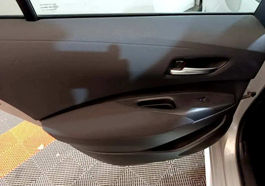 Vue rapprochée de la porte arrière droite gris clair de la Suzuki Swace 1.8 Hybrid Privilege avec poignée intérieure noire.