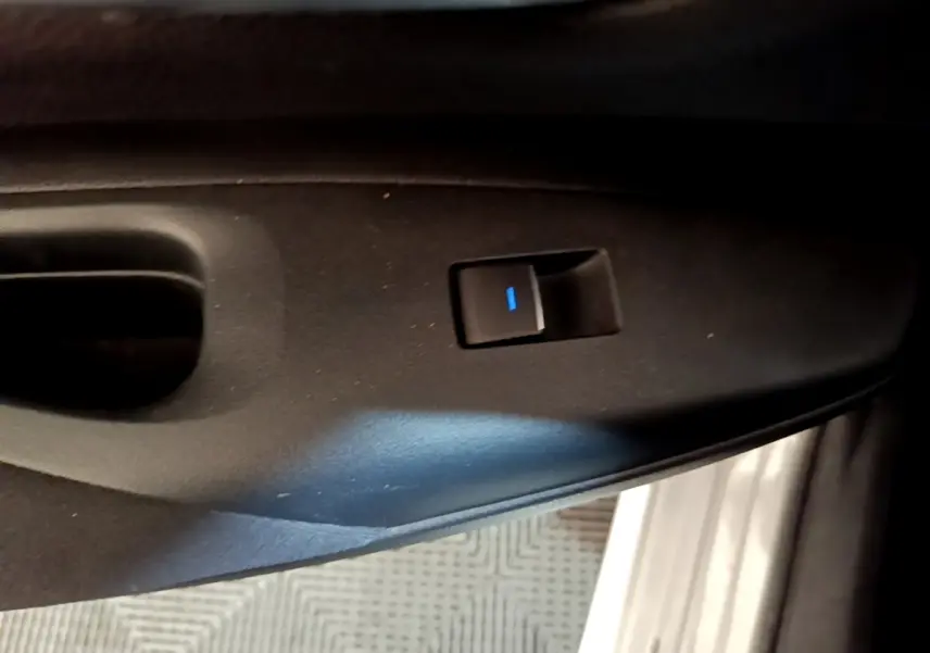 Bouton de commande de lève-vitre noir sur panneau de porte intérieur, détail de la Suzuki Swace gris clair.
