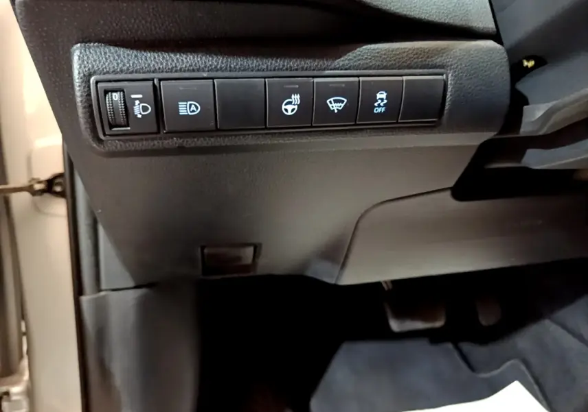 Vue intérieure du tableau de bord côté gauche du Suzuki Swace gris clair, avec commandes d'éclairage et assistance au freinage.