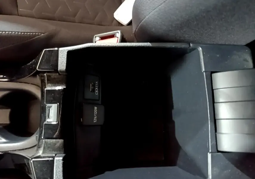 Vue plongeante sur la console centrale noire du Suzuki Swace 1.8 Hybrid Privilege avec prise USB et 12V visible.