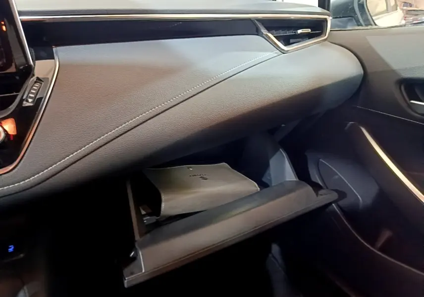 Intérieur de la Suzuki Swace 1.8 Hybrid Privilège 2021, vue côté passager sur la boîte à gants ouverte et tableau de bord gris.