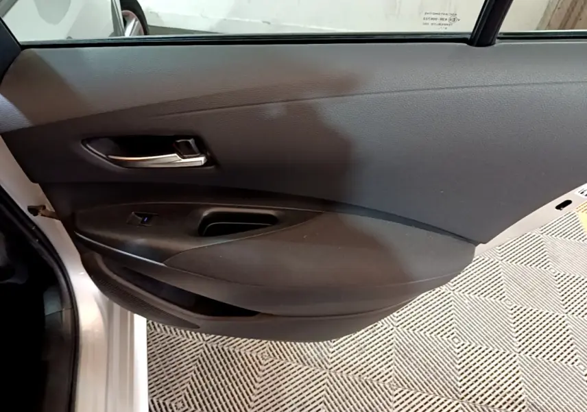 Gros plan sur la porte intérieure côté gauche du Suzuki Swace 1.8 Hybrid Privilege avec garniture noire et poignée argentée.