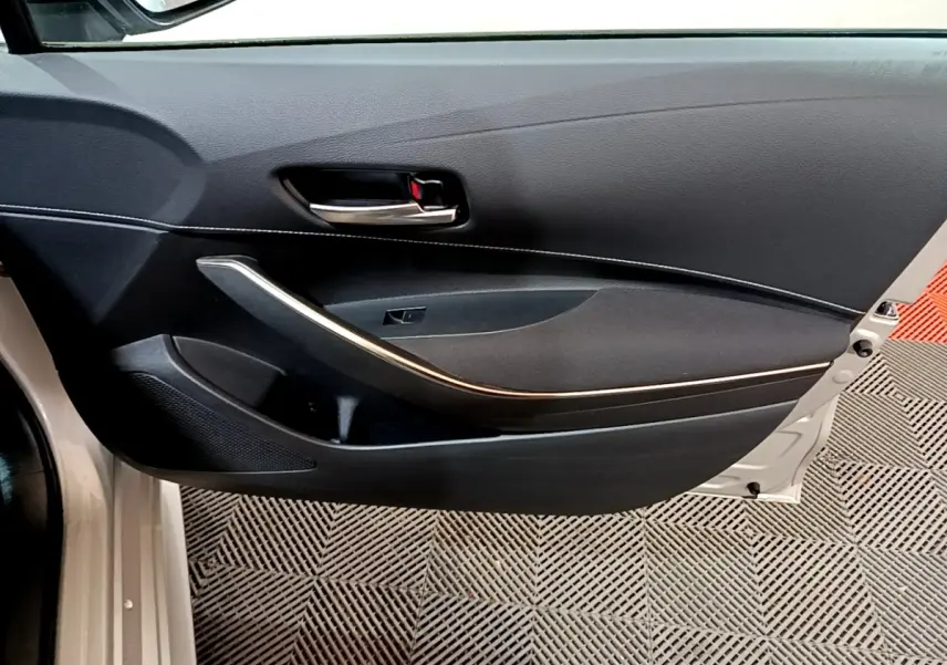 Vue intérieure de la porte avant gauche noire avec poignée chrome et insert gris clair du Suzuki Swace 1.8 Hybrid Privilege.