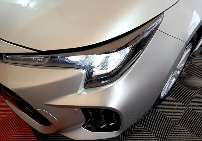 Vue 3/4 avant droit d'une Suzuki Swace gris clair mettant en valeur son phare LED et la calandre inférieure.