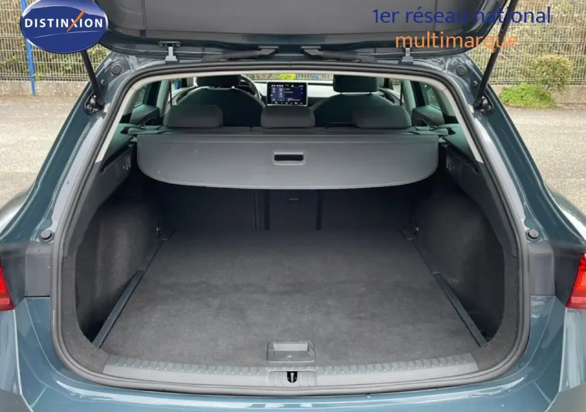 Coffre ouvert vu de l'arrière d'une SEAT LEON ST 2.0 TDI bleu fjord, montrant l'espace de chargement vide et la plage arrière.