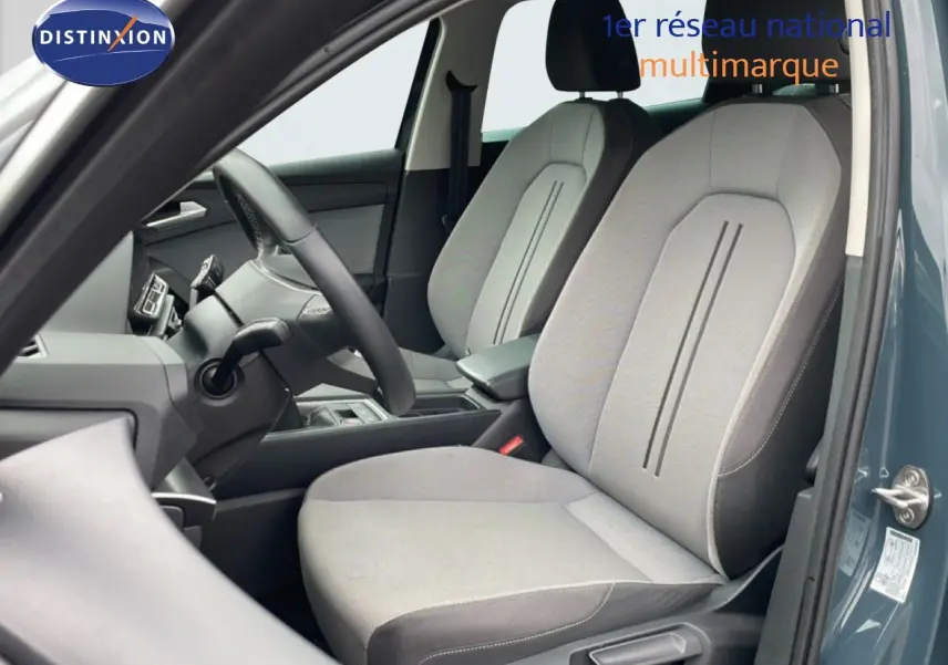 Vue intérieure côté conducteur du SEAT LEON ST 2025 bleu Fjord, mettant en valeur les sièges tissu gris clair et tableau de bord.